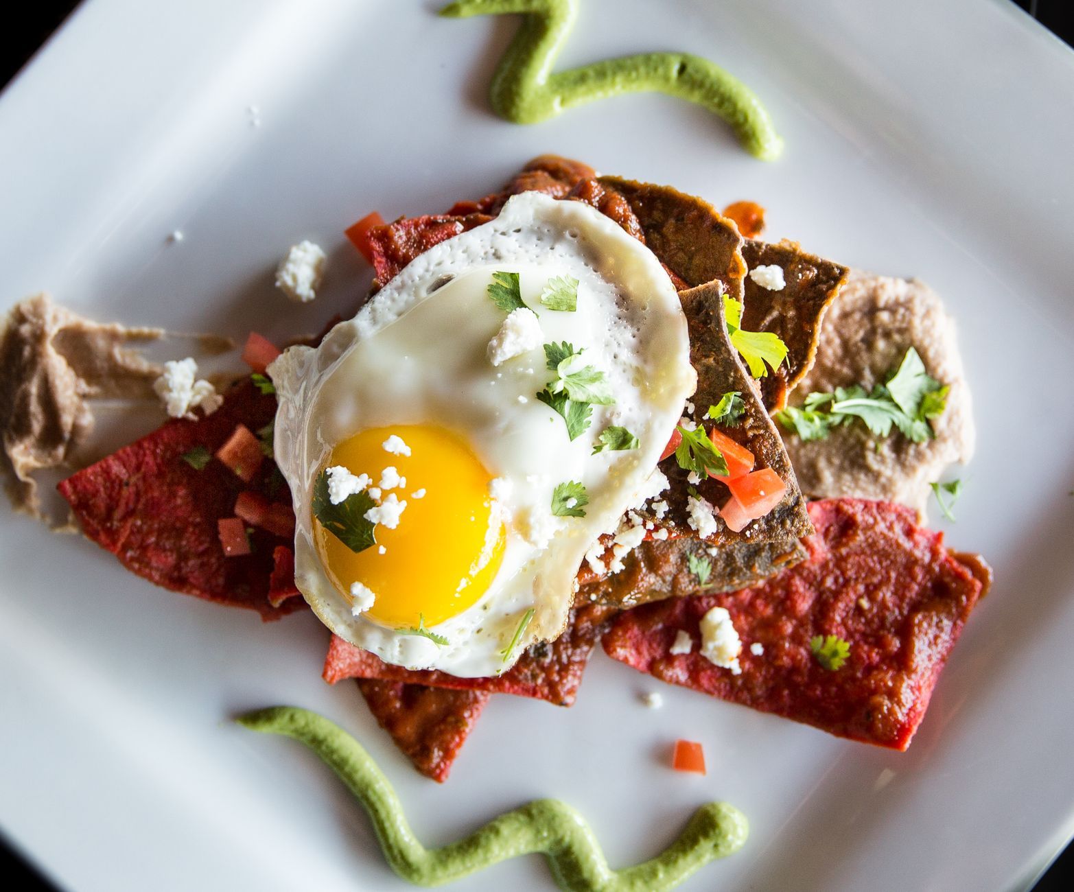 A plate of chilaquiles topped with crema and queso fresco
