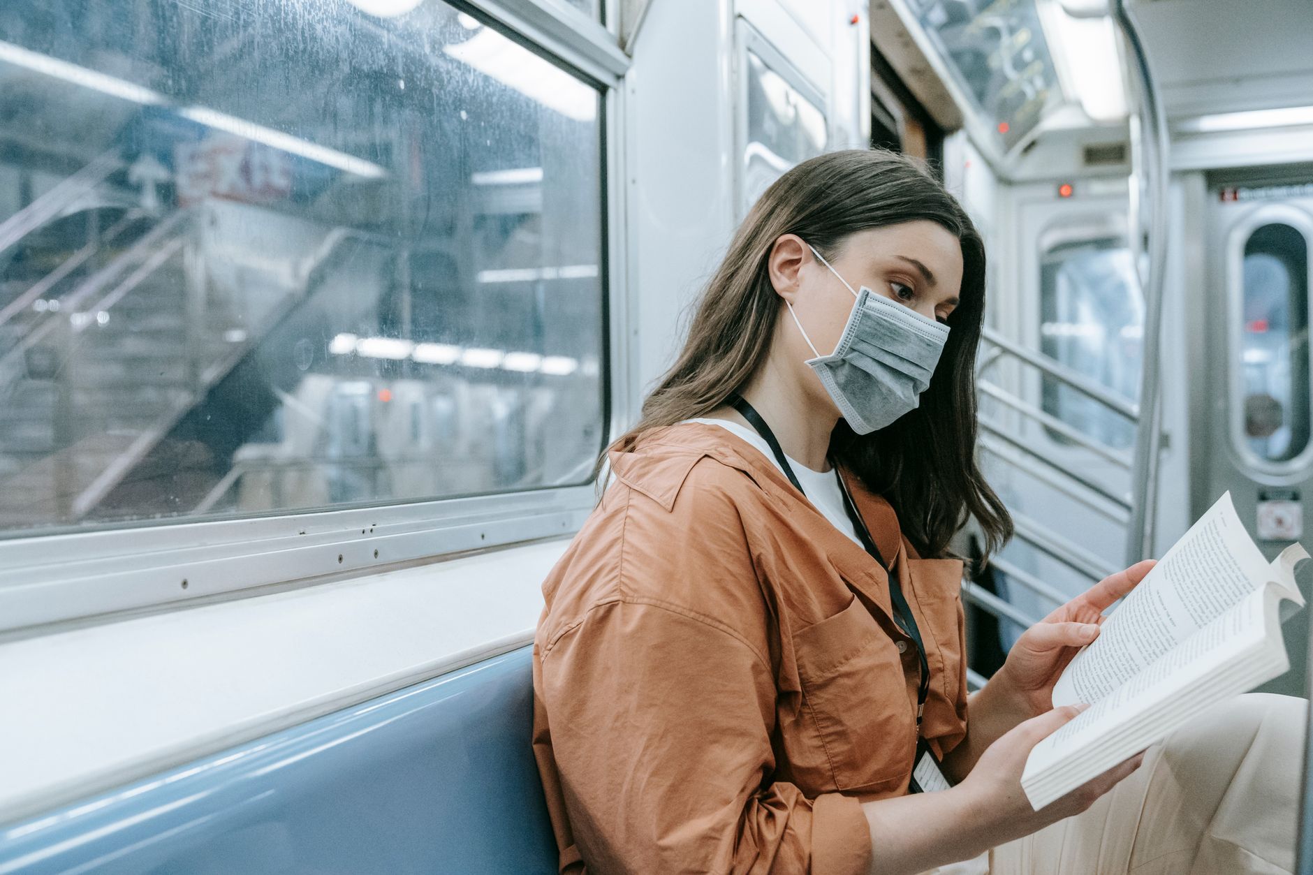 A person reading on public transit, holding a paperback book